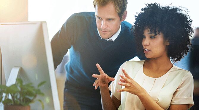 Office workers discuss at a computer