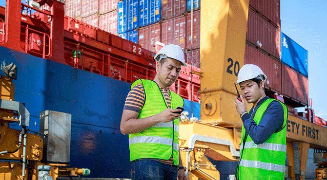 Two workers on handsets at a shipyard