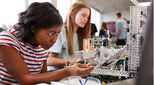 Two Female College Students Building Machine In Science Robotics Or Engineering Class