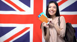 Union Jack flag with an international student standing in front of it holding a passport