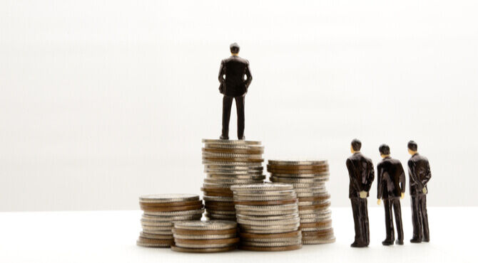 Image of four figures and one standing apart on pile of coins