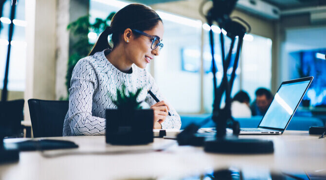 woman looking at a computer and making notes