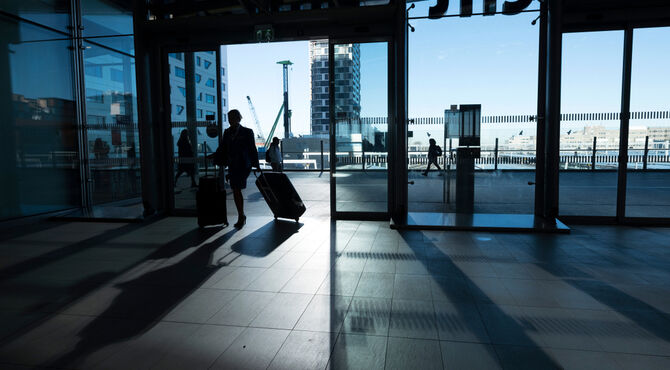 Silhouetted image of woman traveller reflected in glass against urban landscape