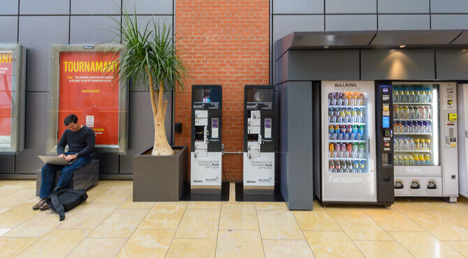 Person on laptop in Bullring Centre Birmingham next to mobile phone charging unit