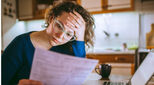 oung brunette curly female reading her bill papers, looking stressed