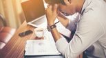 Image of stressed man with head in his hands
