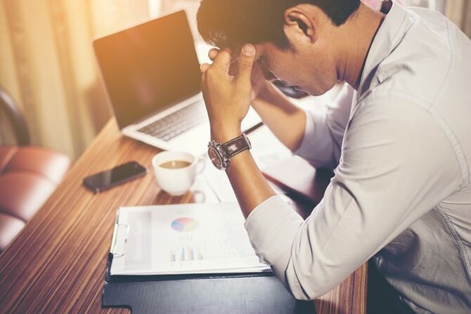 Image of stressed man with head in his hands