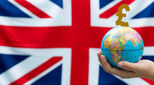 World globe and pound symbol in front of British flag.
