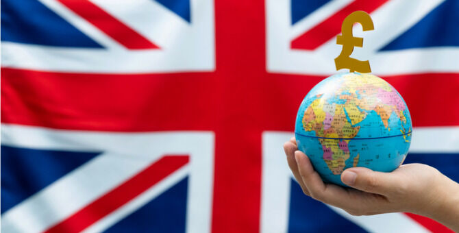 World globe and pound symbol in front of British flag.